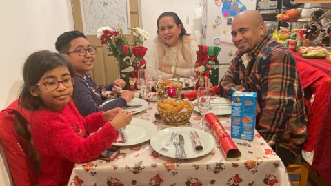 A woman and man sit with their children, a boy and a girl, around a dinner table at Christmas time