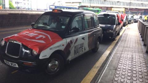 Taxis in Birmingham displaying RMT flags and posters