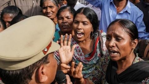 People argue with police over a protest against the alleged rape and murder of a 27-year-old woman