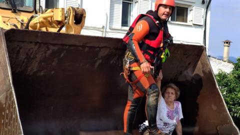 A rescue team uses an excavator to remove an elderly woman from her flooded house, after a rainstorm hit the area of Mourtzi, on Evia Island, Greece, 09 August 2020.