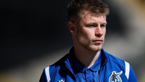 Calum MacDonald in a Bristol Rovers tracksuit walking into the ground ahead of a game