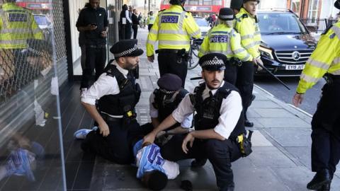 Young man being held on the ground by three police officers.