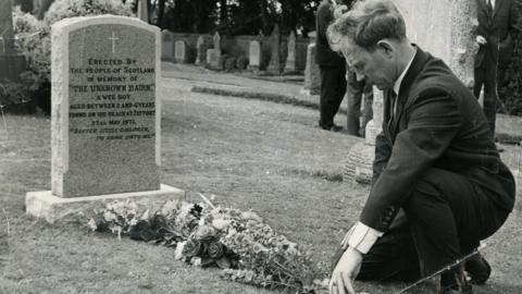 Postman Ian Robertson at the grave of the Unknown Bairn in 1971