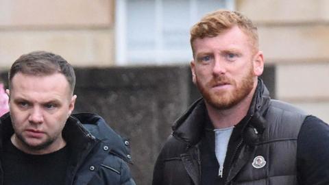 Eddie Lyons, left, who has short, dark hair and is looking slightly off camera. He is wearing a dark jacket over a dark t-shirt. Ross Monaghan, right, is looking straight at the camera. He has ginger hair and a ginger beard and is wearing a dark gilet over another dark top.