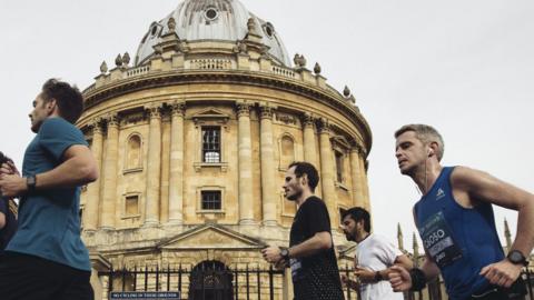 Runners passing the Radcliffe Camera building in Oxford