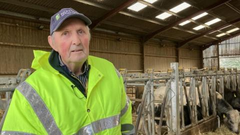 Emyr in a hi-vis jacket in his cattle shed