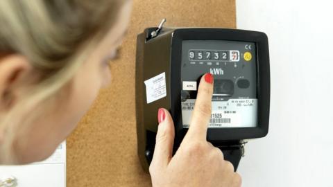 Woman checking electricity meter