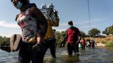 Migrants seeking asylum in the US walk in the Rio Grande river near the International Bridge between Mexico and the US as they wait to be processed, in Del Rio, Texas, on 16 September 2021