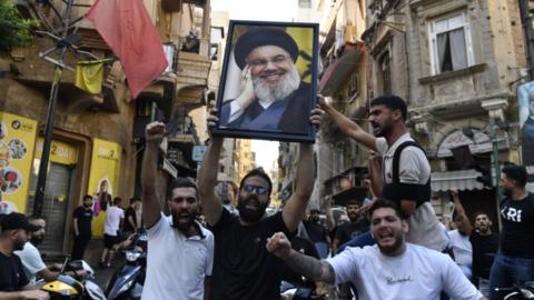 Men raise a photo of Nasrallah in the street