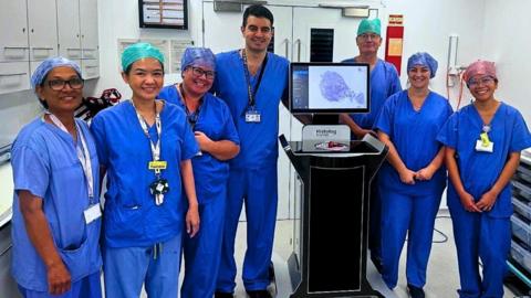 Seven surgeons at the Royal Surrey County Hospital standing next to the Histolog Scanner.