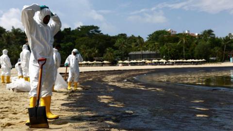 Workers in full body suits cleaning up the oil spill at the tourist attraction Tanjong Beach on Sunday