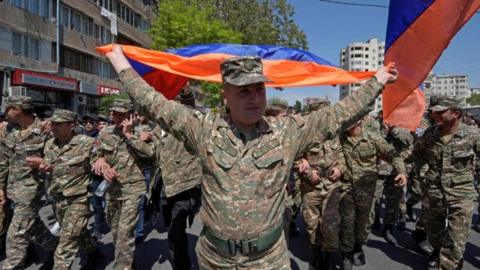A soldier waves an Armenia flag during a protest