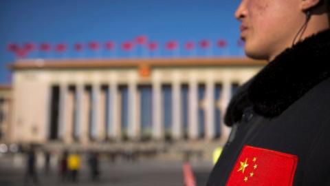 In this 12 March 2017 photo, a security official with a Chinese flag patch on his jacket stands guard outside of the Great Hall of the People before a plenary session of the National People's Congress (NPC) in Beijing, China.