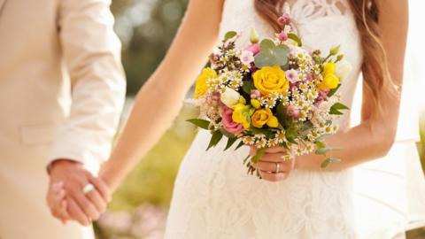 A stock picture of an unidentified straight couple holding hands at their wedding