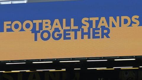 The message 'Football Stands Together' displayed on a screen at a Premier League game