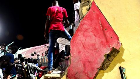 a man standing on a section of collapsed wall