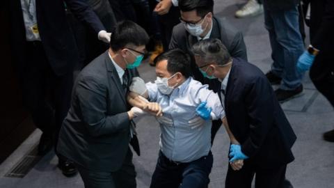 A pro-democrat lawmaker is restrained by security guards at the Legislative Council in Hong Kong