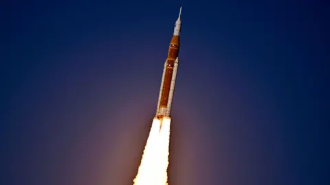 A close up of the rocket taking off, with a dark sky in the background