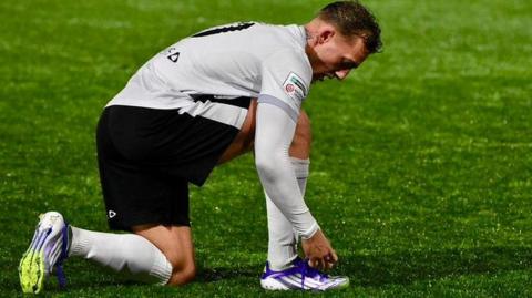 Merthyr Town striker Ricardo Rees tying the laces on his purple boots