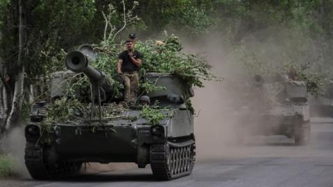 Ukrainian servicemen ride atop self-propelled guns