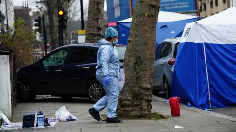 Forensic teams near a vehicle on the pavement