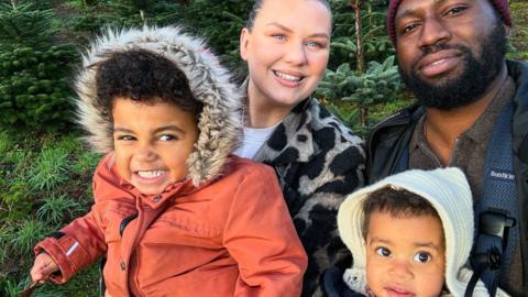 A family with two young children smile at the camera 