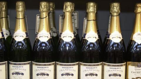 A row of champagne bottles on a shop shelf