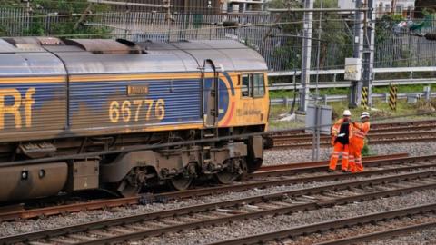 Railway workers stood next to the derailed freight train at West Ealing