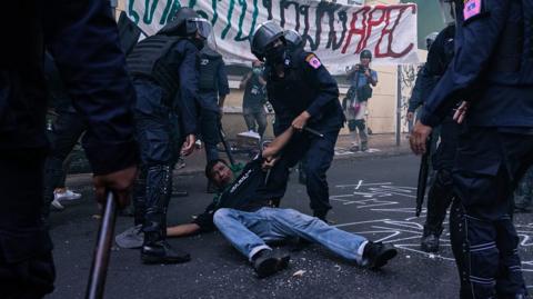 protester on the ground held by police