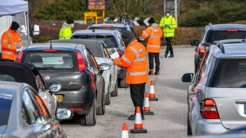 Testing staff hand out kits to motorists attending a surge testing centre at the Science Park, Emersons Green, in Bristol, Gloucestershire.