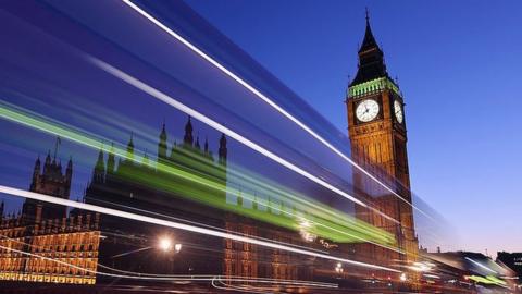 A bus travels along Westminster Bridge past the Houses of Parliament