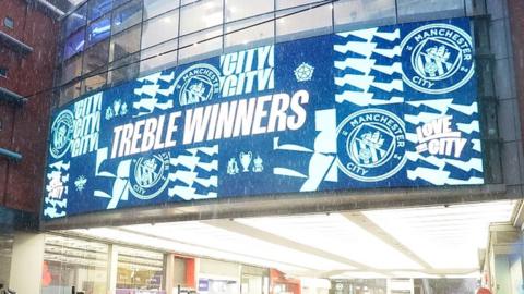 sign outside Manchester Arndale proclaiming City as treble winners