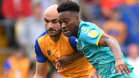 Timmy Abraham of Newport County is tackled by Mansfield's Farrend Rawson