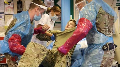 Marine Commando on medical bed surrounded by medics