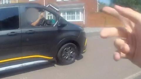 Police officer's hand hailing a lift from a black van.