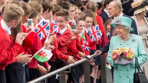 The Queen, Prince Philip and school children holding Welsh and Union flags