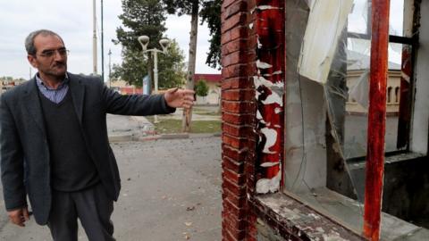 local resident stands in an empty street near a house allegedly damaged by an alleged recent shelling in the settlement of Bakharly in Agdam region in Nagorny Karabakh
