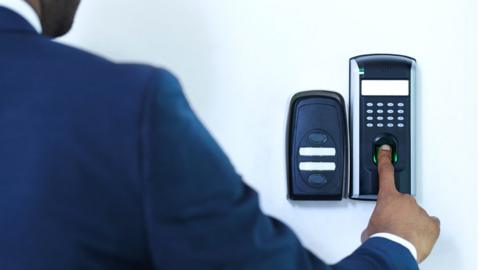 A man using a fingerprint scanner on a wall