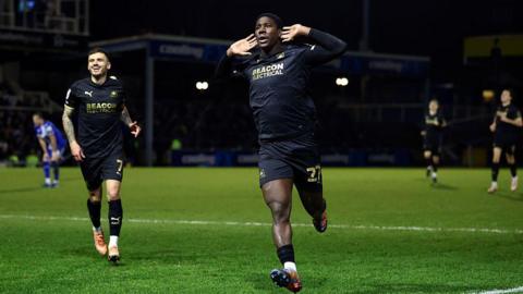Plymouth Argyle's Aribim Pepple cups his hands to his ears as he runs to the fans to celebrate his match-winning goal.