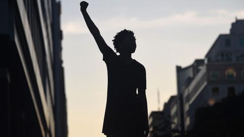 A file photo of a protester silhouette raises a fist during a protest against police brutality and the death of George Floyd.