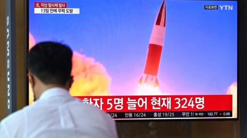 People watch a television news broadcast showing file footage of a North Korean missile test, at a railway station in Seoul on September 28, 2021