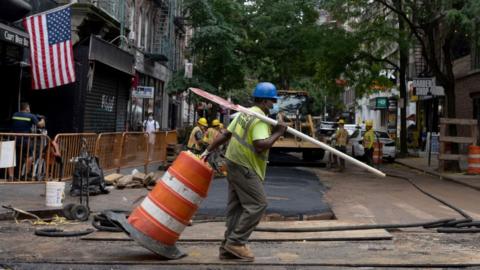 Construction worker drags cone