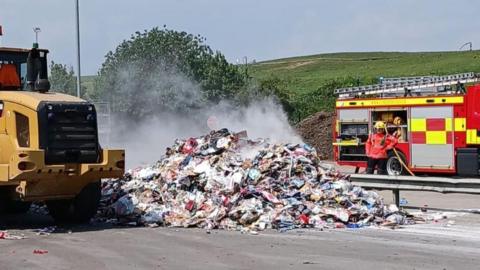 A pile of waste, tipped from a waste struck, smoulders.