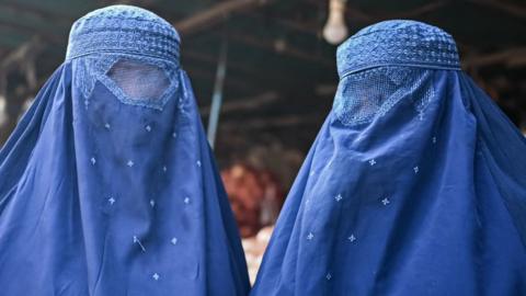 Afghan burqa-clad women are pictured at a market in Kabul on 20 December