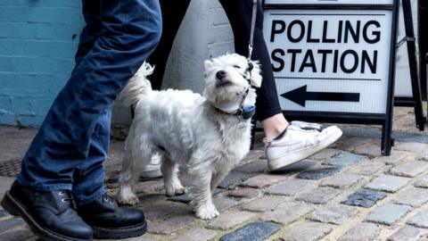 Voters leave a polling station with a dog on 4 May 2023 in Eton, UK