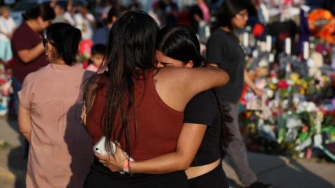 Women embrace at a memorial to those killed in the Uvalde mass shooting