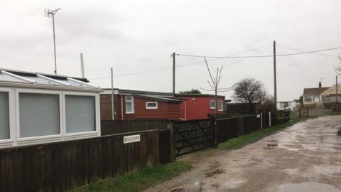 Single-storey chalet buildings with boundary fence and road