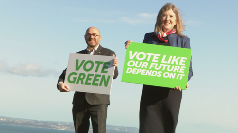 Two Scottish Greens hold signs saying "Vote Green"
