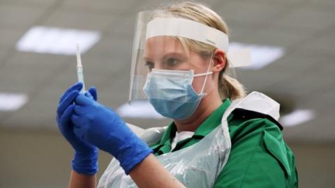 A volunteer holds a syringe