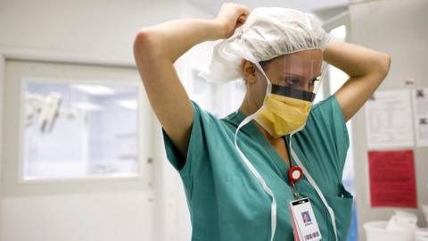 Stock image of a nurse putting on a face covering